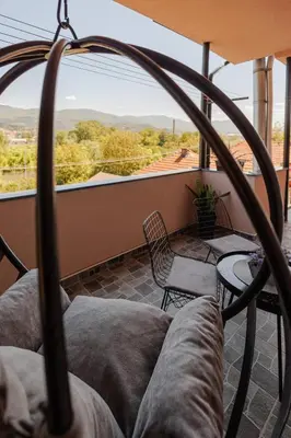 a balcony with a couch and chairs and a large window at Apartman Pepa in Pirot