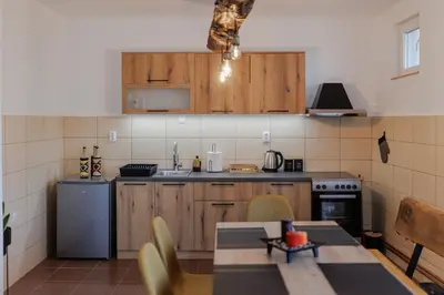 a kitchen with wooden cabinets and a table and a refrigerator at Apartman Pepa in Pirot