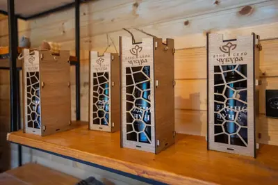 four wine bottles in boxes on a wooden shelf at Etno selo Čubura in Čubura
