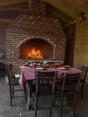 a table and chairs in front of a brick fireplace at Etno selo Čubura in Čubura