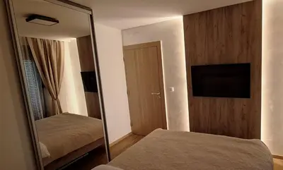 a mirror in a bedroom with a bed and a television at Apartman Zelena laguna in Vrnjačka Banja