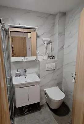 a white bathroom with a toilet and a sink at Apartman Zelena laguna in Vrnjačka Banja