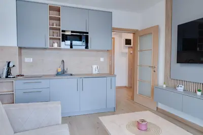 a kitchen with white cabinets and a tv on a wall at Apartmani Central A50 & Free Parking in Vrnjci