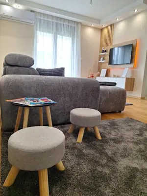 a living room with a couch and two stools at Duma Apartmani 2 Vrnjačka Banja in Vrnjačka Banja