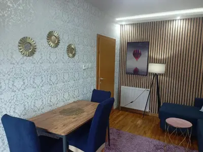 a dining room with a wooden table and blue chairs at Emilija Apartments in Soko Banja