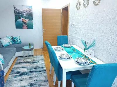 a dining room with a white table and blue chairs at Emilija Apartments in Soko Banja
