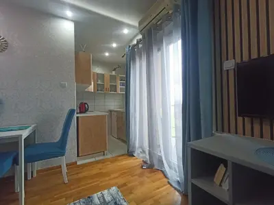 a room with a table and a blue chair and a kitchen at Emilija Apartments in Soko Banja