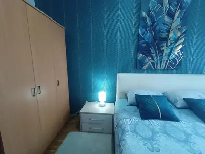 a bedroom with a bed with a blue accent wall at Emilija Apartments in Soko Banja