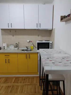 a kitchen with yellow cabinets and a sink and a table at Apartman Sunshine in Vrnjačka Banja