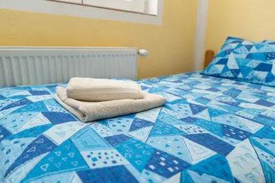 a blue and white bed with a towel on it at Sobe Joksimović in Vrnjačka Banja