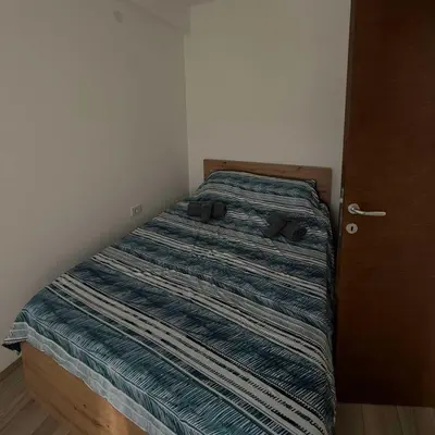 a bed with a striped comforter in a bedroom at apartmanjagodinaana 2 in Trnava