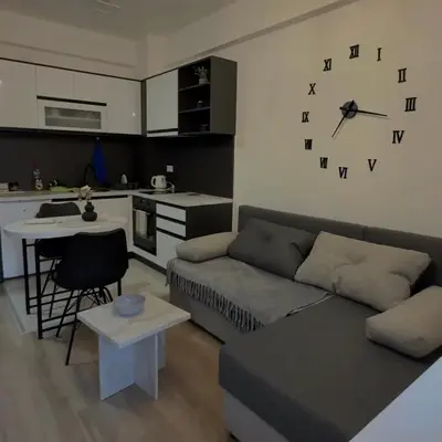 a living room with a couch and a clock on the wall at apartmanjagodinaana 2 in Trnava