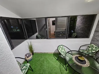 a balcony with a table and chairs and a room with windows at Apartman Tara in Soko Banja