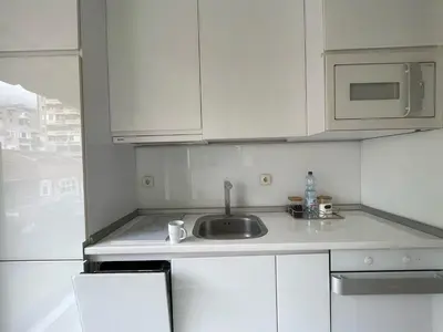 a white kitchen with a sink and a microwave at LUCHIANO apartments in Niš