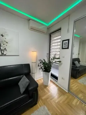 a living room with a black couch and a mirror at LUCHIANO apartments in Niš