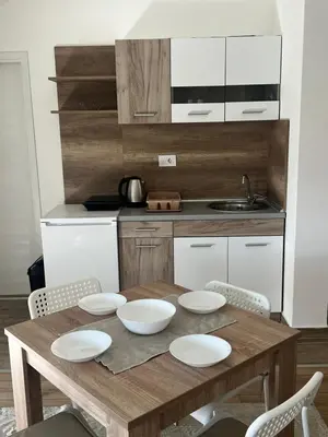 a wooden table with four white bowls on it in a kitchen at S&M apartman FREE PARKING in Vranje