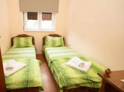 two beds in a room with green sheets and towels at Apartmani Votor in Vrnjačka Banja