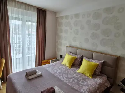 a bedroom with a bed with yellow pillows and a window at Gracia apartman in Vrnjci