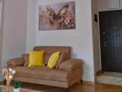 a brown couch with yellow pillows in a living room at Gracia apartman in Vrnjci