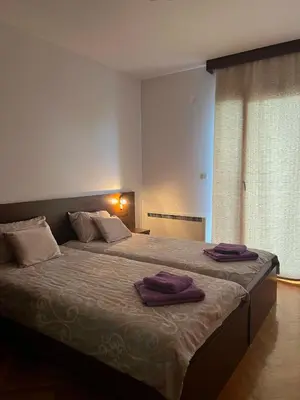 a bedroom with a large bed with purple towels on it at Apartman Tomić Vrnjacka Banja in Vrnjci