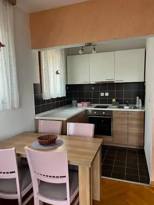 a kitchen with a wooden table and pink chairs at Apartman Tomić Vrnjacka Banja in Vrnjci