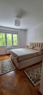a bedroom with a large bed and two windows at Apartment 4 in Niš