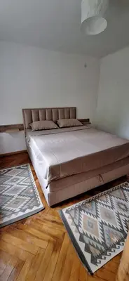 a large bed in a bedroom with wooden floors at Apartment 4 in Niš