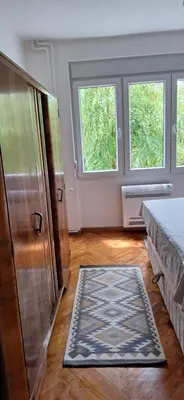 a bedroom with a bed and a dresser and two windows at Apartment 4 in Niš