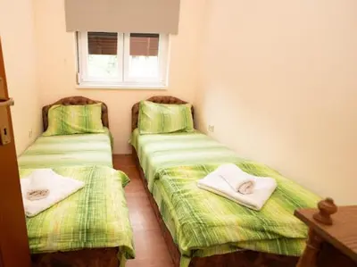 two beds in a room with green sheets and towels at Apartmani Votor in Vrnjačka Banja
