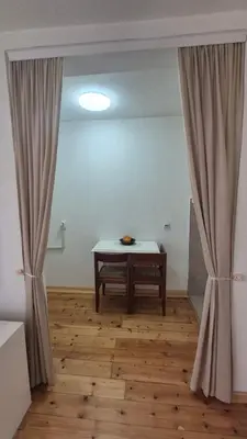 a room with a table and curtains on a wooden floor at Studio VA2016 in Kruševac