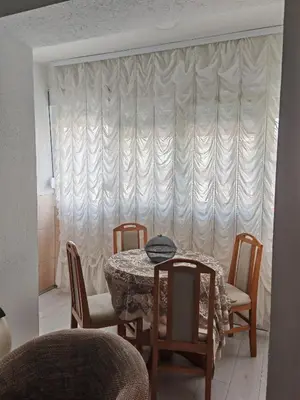 a dining room with a table and chairs and a curtain at Apartman-Stan in Jagodina