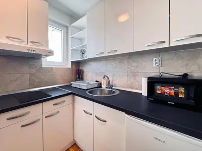 a kitchen with white cabinets and a sink and a microwave at Azure in Vrnjačka Banja