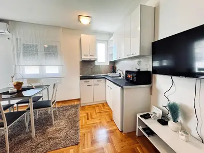 a kitchen with white cabinets and a dining table at Azure in Vrnjačka Banja