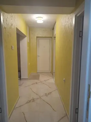 an empty hallway with yellow walls and a marble floor at Apartman Orhideja in Knjazevac.