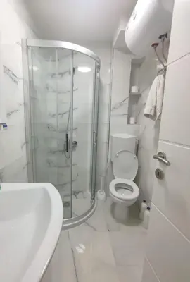 a white bathroom with a shower and a toilet at Apartman Orhideja in Knjazevac.