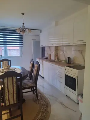 a kitchen with white cabinets and a table and chairs at Apartman Orhideja in Knjazevac.