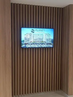 a television on a wall with a building on it at LanDan Planet - free parking in Niš