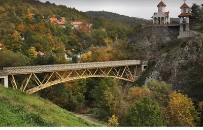 a bridge on top of a hill with houses and trees at Apartmani Rada in Prolomska Banja