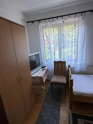 a bedroom with a bed and a television and a chair at Apartmani Rada in Prolomska Banja