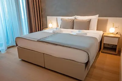 a bedroom with a large bed with two lamps on it at ZEPTERME Promenada - Šetalište in Vrnjačka Banja