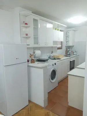 a kitchen with white cabinets and a washer and dryer at Apartmani Milica in Kraljevo