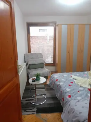a bedroom with a bed and a chair and a table at Apartmani Milica in Kraljevo