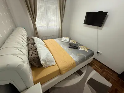 a bedroom with a bed with a television on the wall at Apartman Delux in Soko Banja