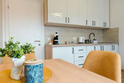 a kitchen with white cabinets and a wooden table with chairs at Apartman Stevanovic in Vrnjačka Banja