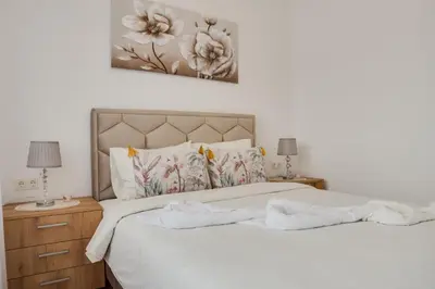 a bedroom with a bed with white sheets and flowers at Apartman Stevanovic in Vrnjačka Banja