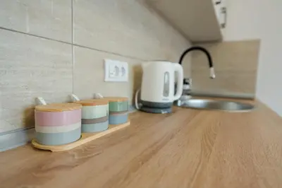 a kitchen counter with four cups on a wooden shelf at Apartman Stevanovic in Vrnjačka Banja