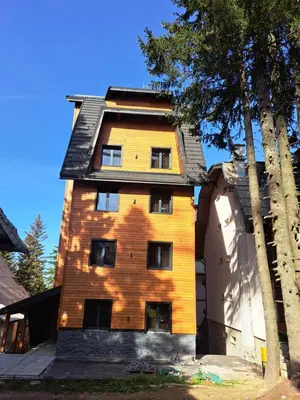 a tall brick building with a door and trees at Casa di legno apartman 3,6,9 in Kopaonik