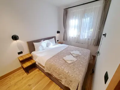a bedroom with a bed with white sheets and a window at Casa di legno apartman 3,6,9 in Kopaonik