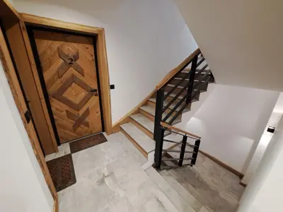 a staircase with a wooden door next to a stair case at Casa di legno apartman 3,6,9 in Kopaonik