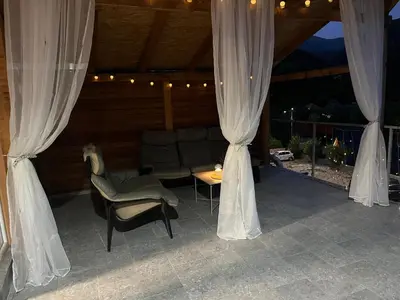 a patio with a couch and a table and curtains at Apartmani Stankovic in Crni Vrh